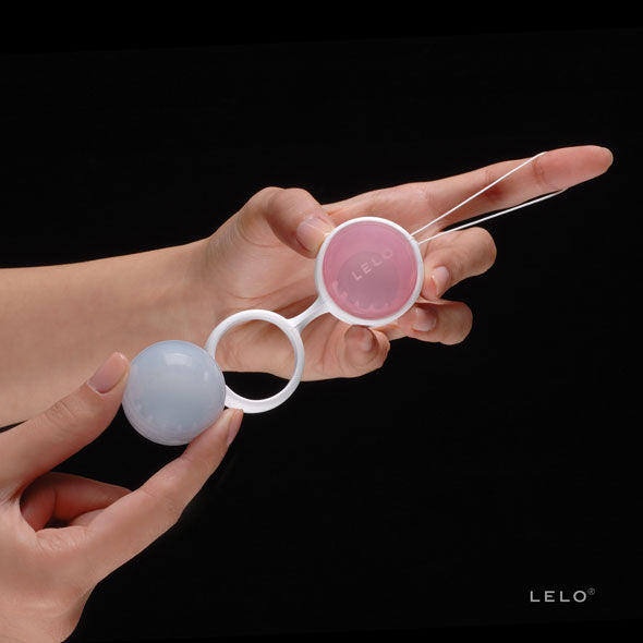 Main tenant le support Luna Beads Mini de Lelo avec une boule rose et une bleue